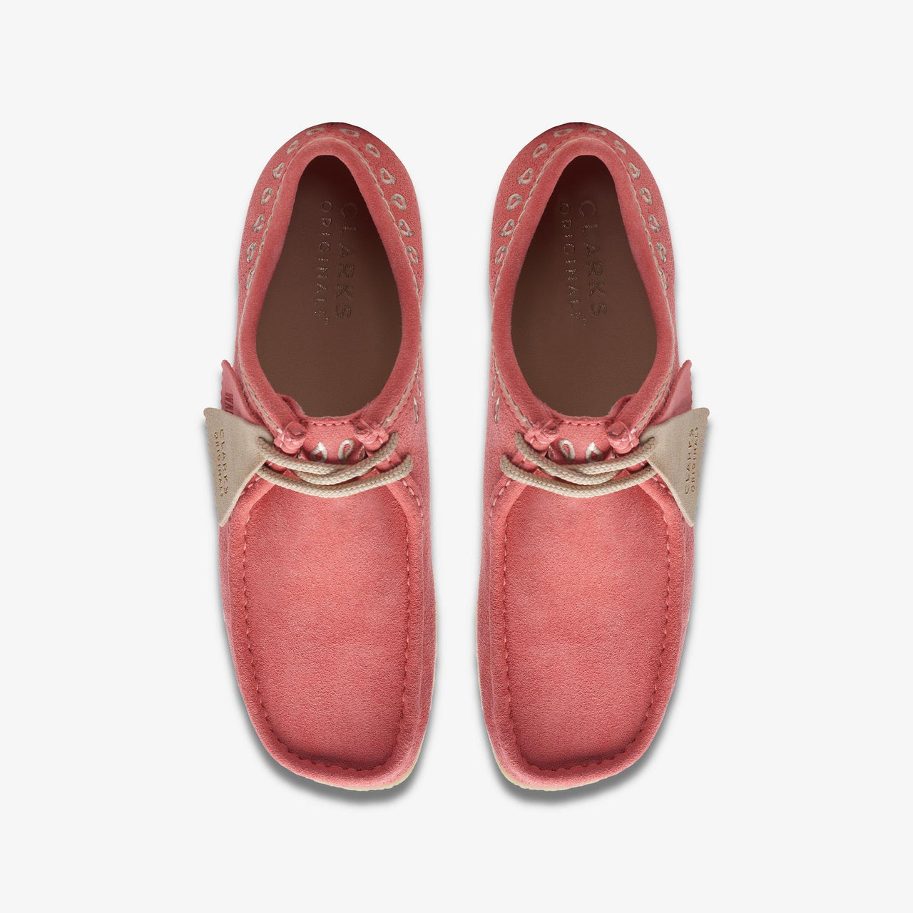 A close-up image of the Mens Clarks Wallabee shoes in pink with intricate embroidery on the upper, showcasing the unique design and craftsmanship